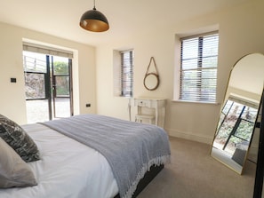 Un dormitorio con cama, espejo, cómoda y ventana con persianas.