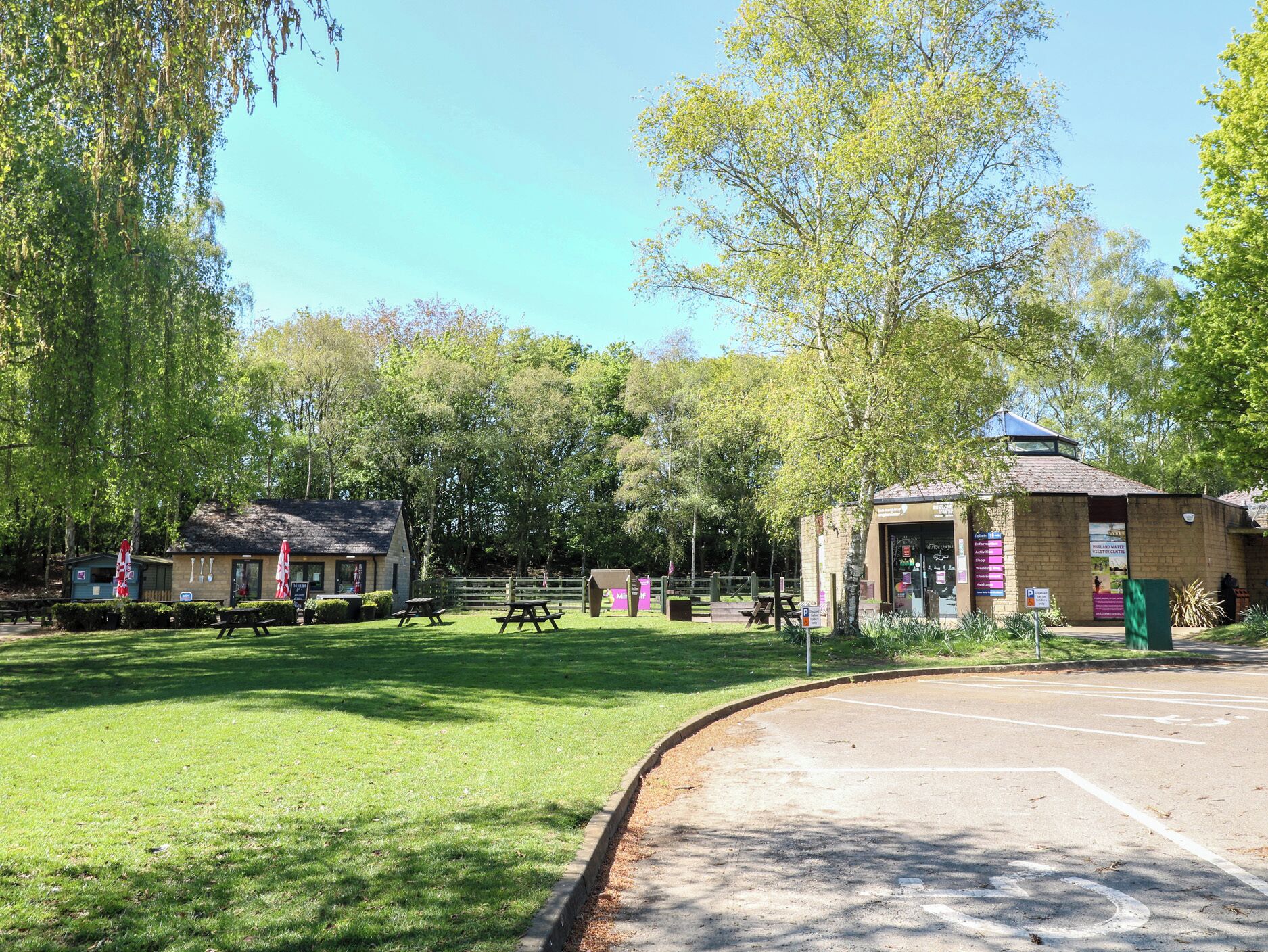A park with picnic tables, a visitor center, and a small building with a pitched roof.