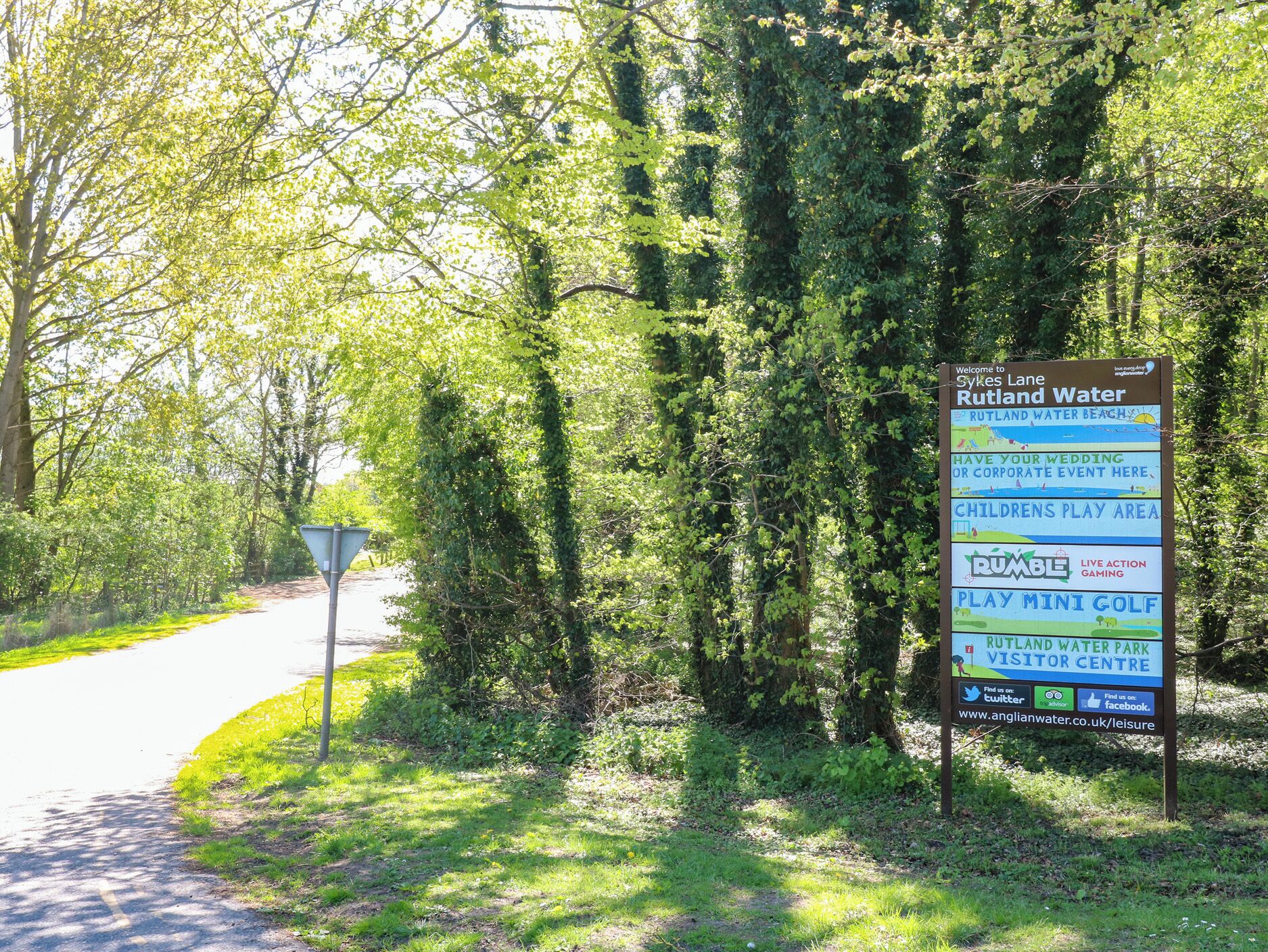 A signboard with information about Rutland Water, including amenities like a children's play area, a mini golf course, and a visitor center.