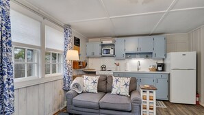Une cuisine compacte avec un canapé gris, un four à micro-ondes, une cuisinière et des placards bleu clair.