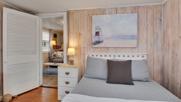 Une chambre à coucher avec un lit, une table de chevet, un tableau et un mur en bois.
