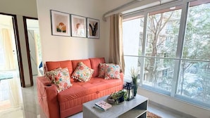 A modern living room with a sofa, coffee table, and artwork on the wall. - Earthen Escape 2BHK near BKC Jio  Gym Access (Mumbai)