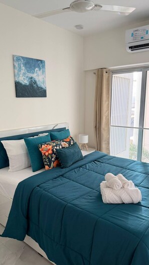 Ein Schlafzimmer mit einem Bett, einem Nachttisch, einer Lampe, einem Fenster mit Vorhängen, einer Klimaanlage und einem Gemälde an der Wand.