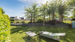 Un espacio al aire libre con césped, una mesa y sillas, rodeado de árboles y una cerca.
