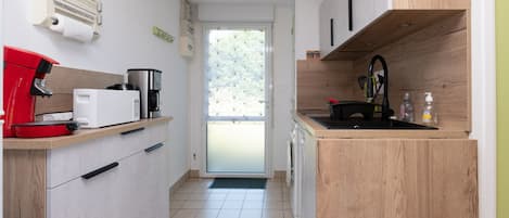 Una cocina compacta con cafetera, microondas y lavamanos.
