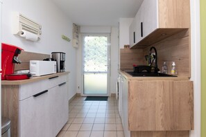 A compact kitchen with a coffee machine, microwave, and sink. - Holiday Home “La Maison Du Haut Pouldu”: Sea View, Shared Pool, Private Terrace (Clohars-Carnoët)
