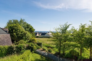 A residential area with houses, a grassy field, and trees. - Holiday Home “La Maison Du Haut Pouldu”: Sea View, Shared Pool, Private Terrace (Clohars-Carnoët)
