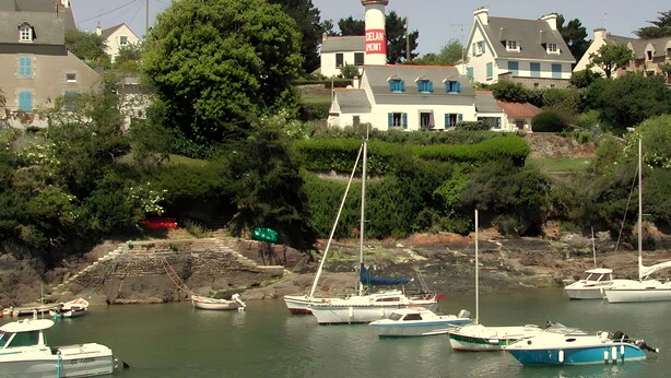 Un puerto con barcos, un faro y edificios al fondo.
