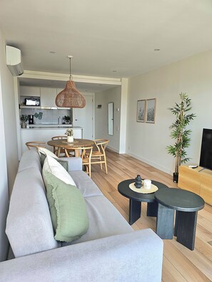 A modern living room with a grey sofa, wooden dining table, and a black coffee table. - Urban 1303 | 2 rooms with garage (Mar del Plata)