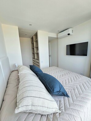 A bedroom with a bed, a TV mounted on the wall, and a built-in wardrobe. - Urban 1303 | 2 rooms with garage (Mar del Plata)