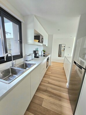 A modern kitchen with a large window, stainless steel appliances, and a wooden floor. - Urban 1303 | 2 rooms with garage (Mar del Plata)