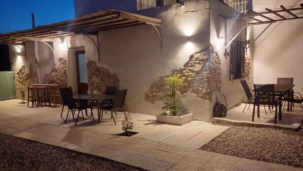 Una zona patio con tavolo e sedie, una pianta in vaso e un muro in pietra.