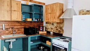Una cucina compatta con mobili in legno, un fornello, un forno a microonde e un lavello.