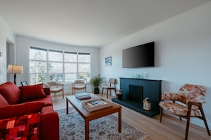 Een woonkamer met een rode bank, een houten salontafel en een open haard.