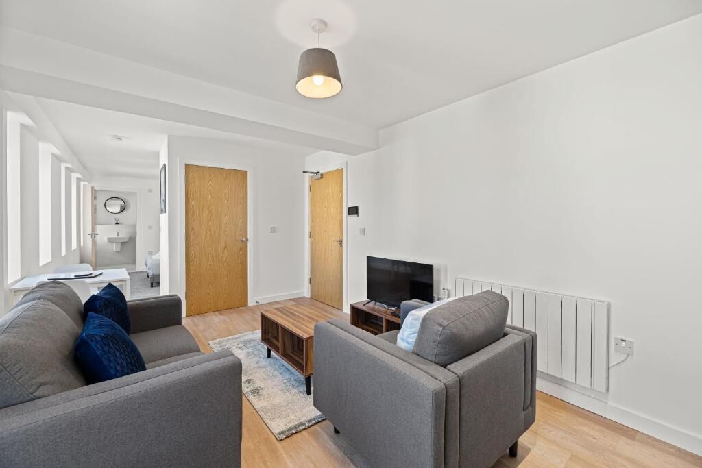 A modern living room with a sofa set, a coffee table, a TV, and a wooden door leading to another room.