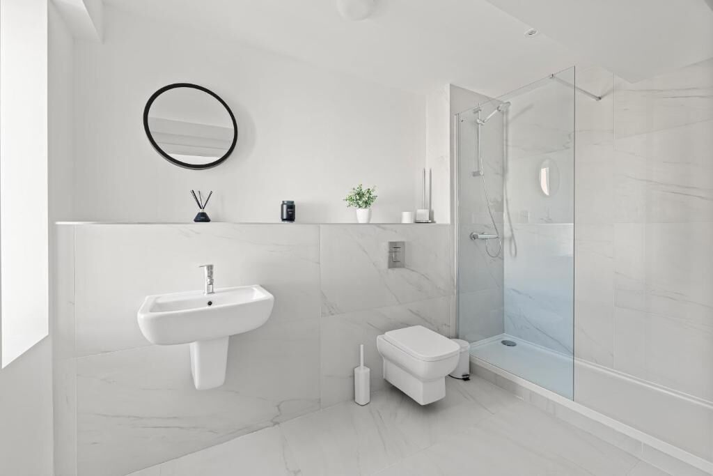 A modern bathroom with a sink, toilet, and glass shower enclosure.