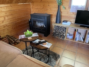 Una sala de estar acogedora con chimenea, televisión y una mesita con adornos.