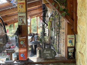 Un edificio de madera rústico con un muro de piedra, un cartel de bienvenida y varios le Routard recomendados desde 2020 hasta 2026.