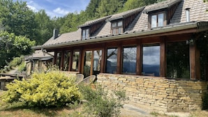 A rustic cabin with stone walls, wooden beams, and large windows.
