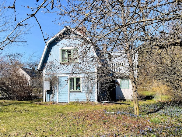 A blue house with a sloped roof, surrounded by trees and a grassy area. - 7 Person Holiday Home in Stanga (Stånga)