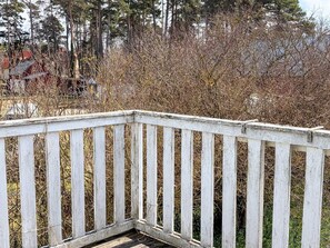 A wooden deck with vertical railings, surrounded by dense shrubbery and trees. - 7 Person Holiday Home in Stanga (Stånga)