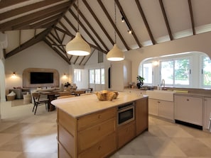 A spacious kitchen with a large island, wooden cabinets, and pendant lighting.