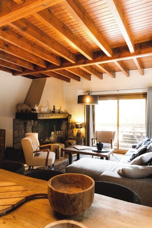 A cozy room with a fireplace, wooden beams, a sofa, and a dining table. - Chalet in the mountains, ideal for families! (Bolquère)