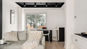 Ein modernes Wohnzimmer mit einer Couch, einem Esstisch und einer Küchenzeile.