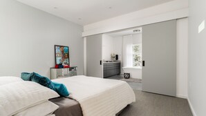 Ein modernes Schlafzimmer mit einem großen Bett, einem Schreibtisch und einem begehbaren Kleiderschrank.
