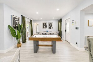 A modern room with a pool table, green plants, and artwork on the walls. - Stylish Home with King Bed l Hockey & Foosball Table (Hollywood)