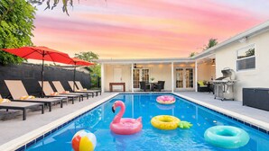 Ein Schwimmbecken mit Liegestühlen, einem Flamingo-Schwimmspielzeug und verschiedenen Luftringen.