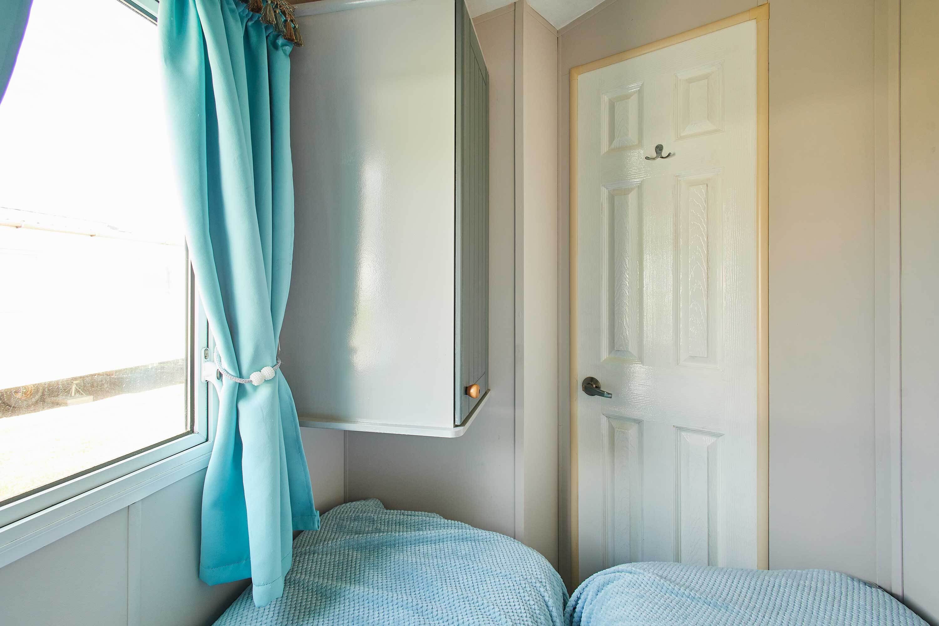 A room with a bed, a wardrobe, a door, and a window with curtains.