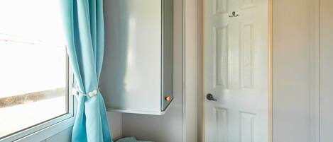 A room with a bed, a wardrobe, a door, and a window with curtains.