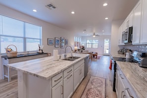 Una cocina moderna con una isla grande, armarios blancos y vista al área de comedor.