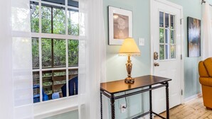 A room with a large window, a table with a lamp, and a door with glass panels. - The Rookery 3602 (Gulf Shores)