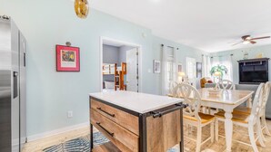 A modern kitchen with a built-in refrigerator, a dining area with a wooden table and chairs, and a ceiling fan. - The Rookery 3602 (Gulf Shores)
