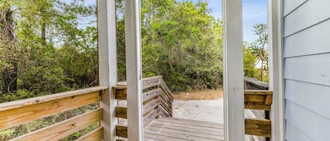 Una terraza de madera que lleva a una playa con vista a abundante vegetación.