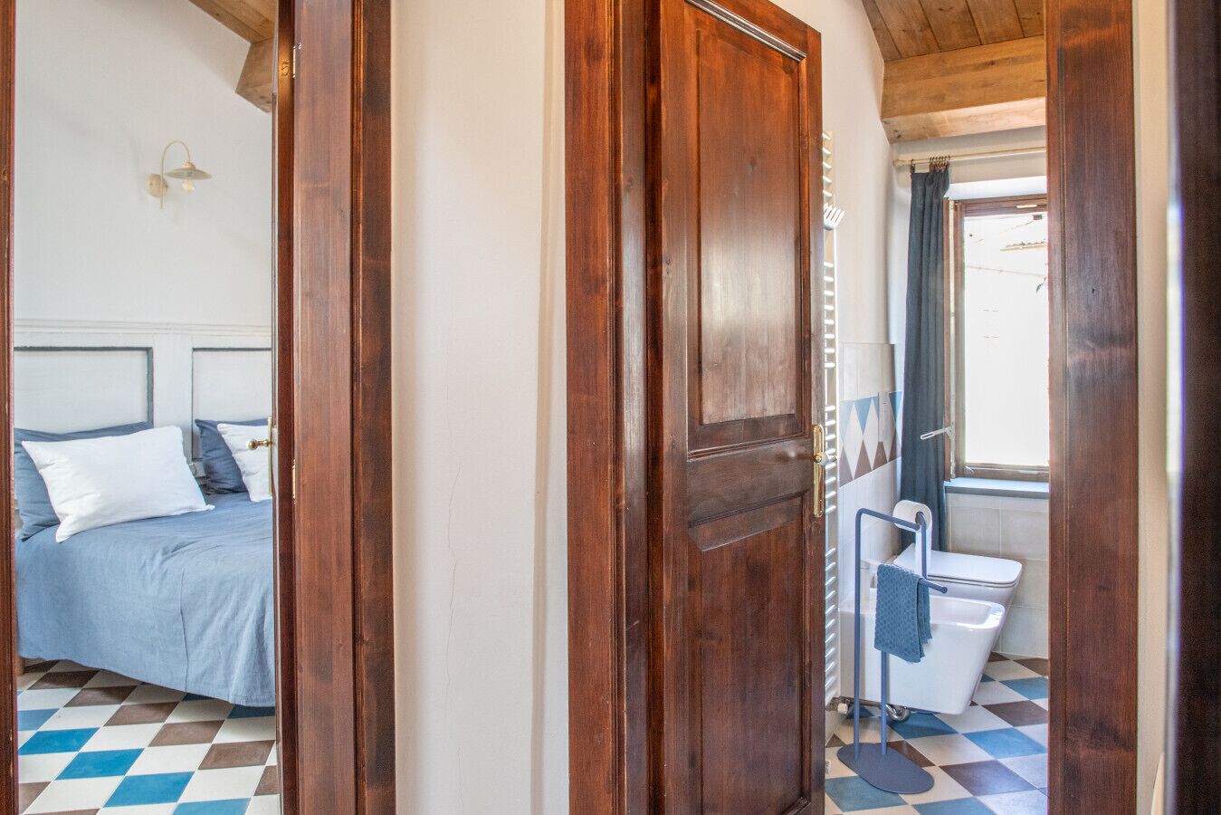 A bedroom with a bed, a wooden door, and a bathroom with a toilet and sink.