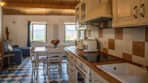 Una cocina con piso a cuadros, techo de madera y vista al campo a través de las ventanas.