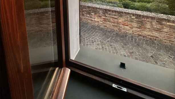 Una habitación con un gran ventanal que ofrece vistas a un atardecer sobre un paisaje montañoso.