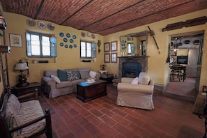 A living room with a fireplace, a sofa, a chair, and a coffee table. - The Willow Bed & Breakfast - Room Tulip (Veruno)