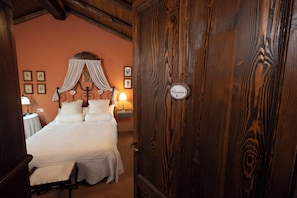 Une chambre à coucher avec un lit à baldaquin, une porte en bois et une table de chevet avec une lampe.