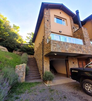 Una casa de dos pisos con fachada de piedra, un garaje y una escalera que lleva a la entrada.