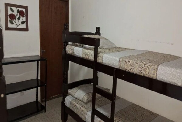 A bunk bed with a patterned mattress, a wooden headboard, and a shelf unit beside it. - Pousada Casa Guacuri (Itupeva)