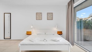 A modern hotel room with a large bed, two wall-mounted light fixtures, a large window with curtains, and a view of the outdoors. - Neudorf Studio Near Kirchberg and Airport (Luxembourg)