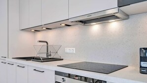 Ett modernt kök med en inbyggd spis, ett handfat och en kaffemaskin.