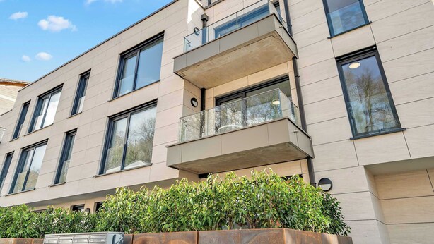 A modern building with multiple windows, balconies, and a well-maintained garden area. - Modern Studio in Neudorf Near Kirchberg (Luxembourg)