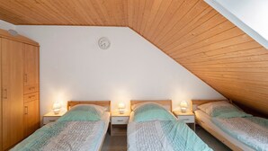 Ein Schlafzimmer mit zwei Einzelbetten, Holzboden, einer Wanduhr und einem Kleiderschrank.
