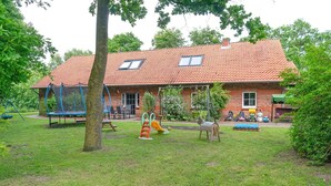 Ein Backsteinhaus mit Ziegeldach, einer Schaukel und einem Spielbereich mit Rutsche.