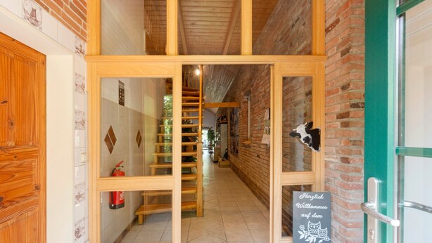 Ein Holzbalkonkorridor mit Treppe, Feuerlöscher und einer Willkommensschild.